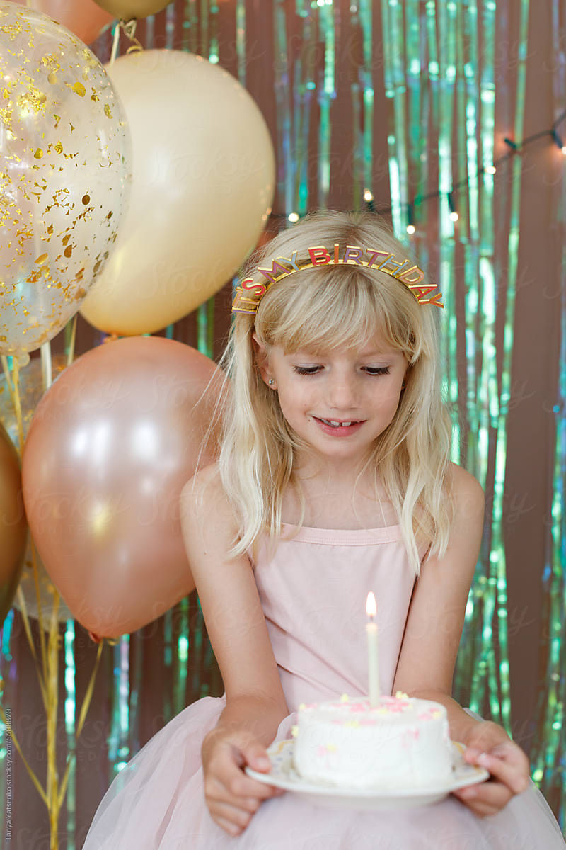 A birthday girl holding a cake with a candle.