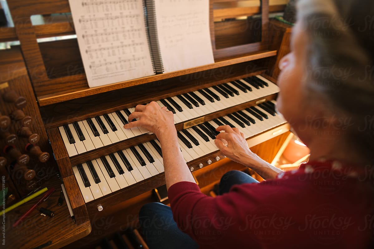Hands of mature woman playing piano and organ in home studio