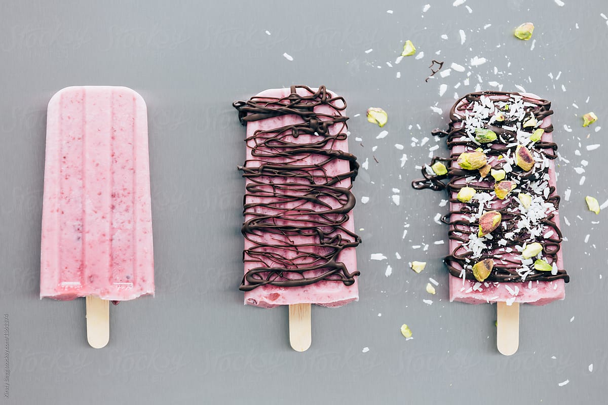 Three cherry popsicles at stages of decoration