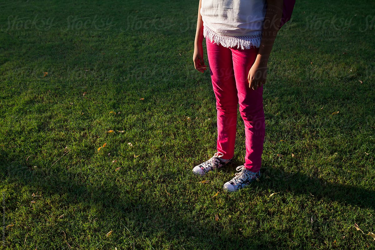 A girl wearing pink trouser and standing on grass