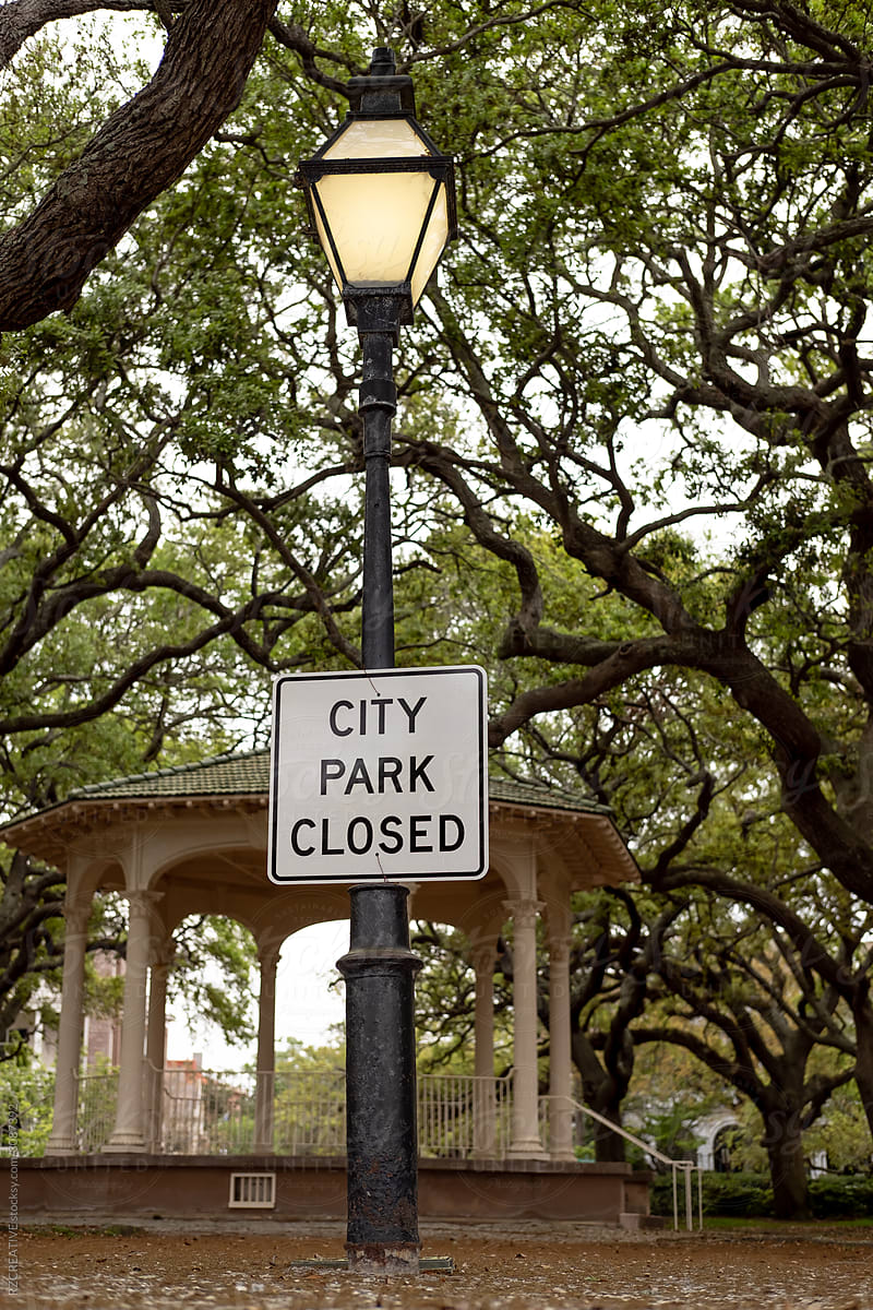 \'City Park Closed\' sign hangs in park.