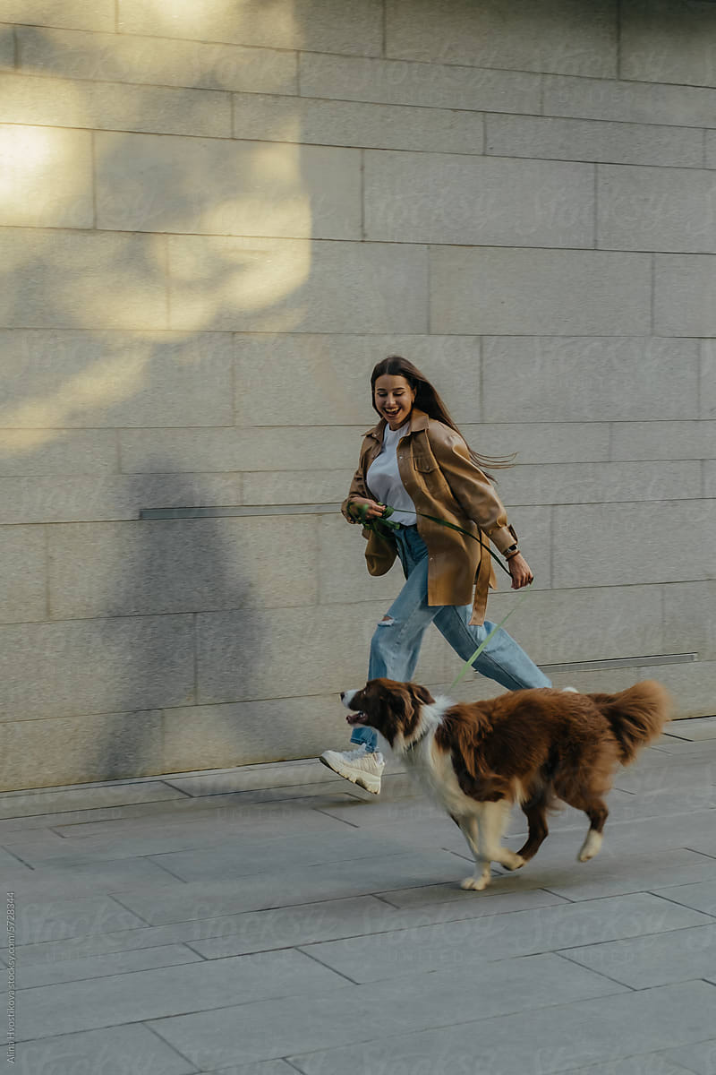Happy woman running with Border Collie dog on street
