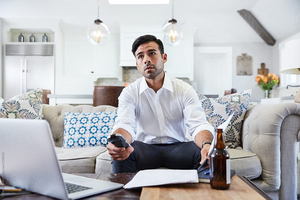 Hispanic businessman watching TV at home after work
