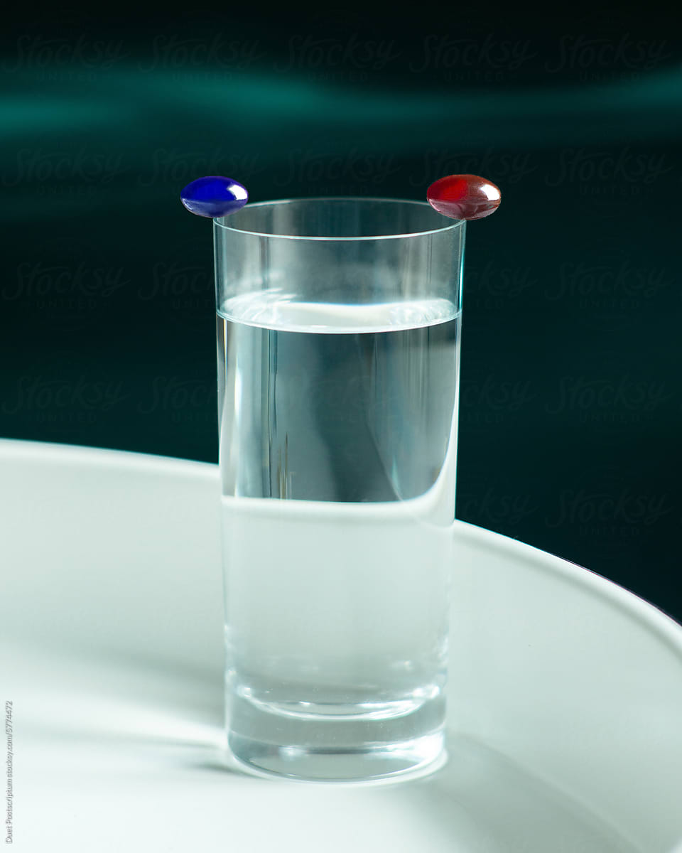 Red and blue pill on the edge of the glass.
