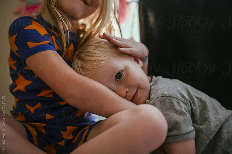 A big sister Cradles her Toddler brother\'s head on her lap
