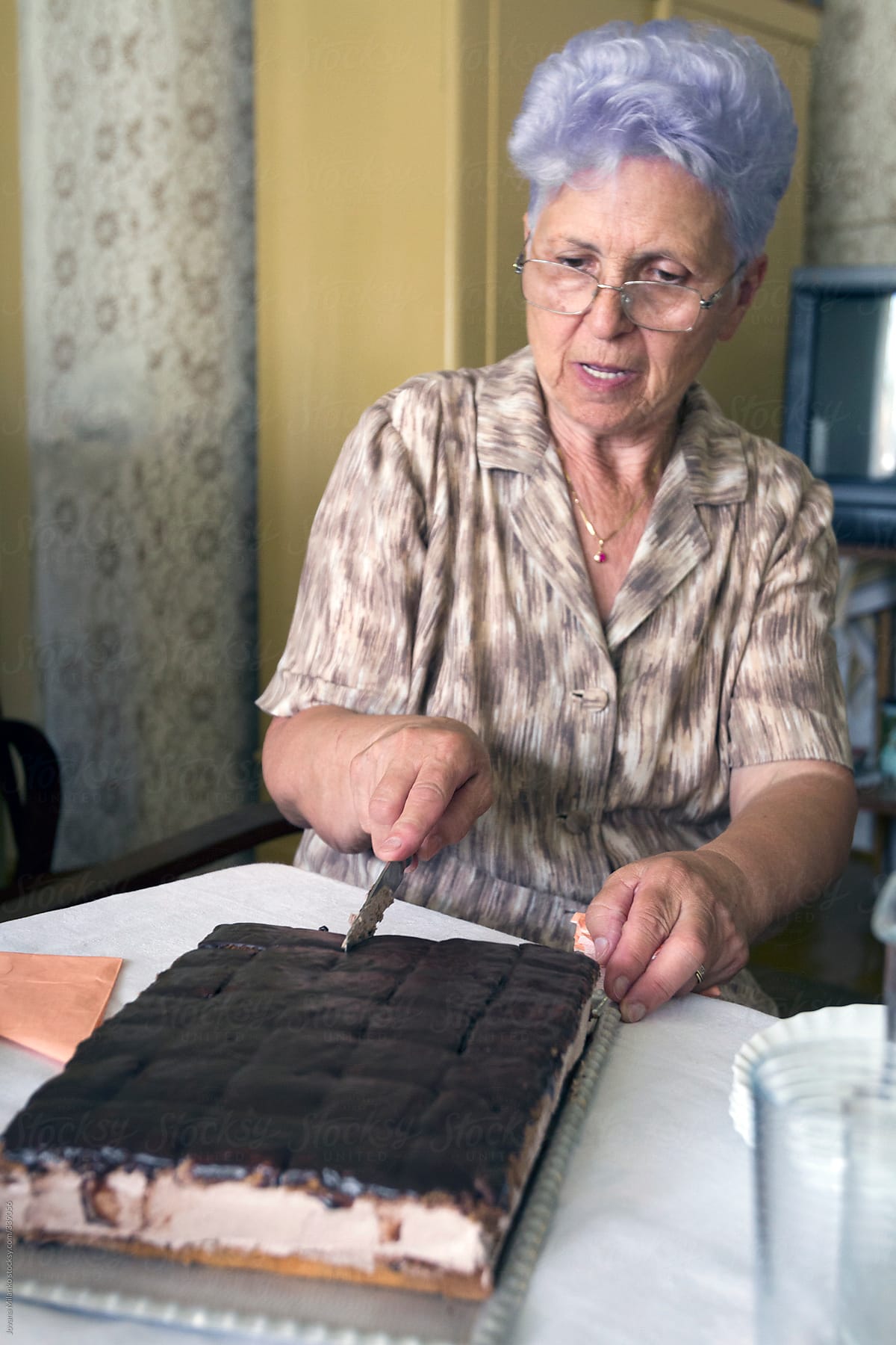 Old woman cutting homemade cake