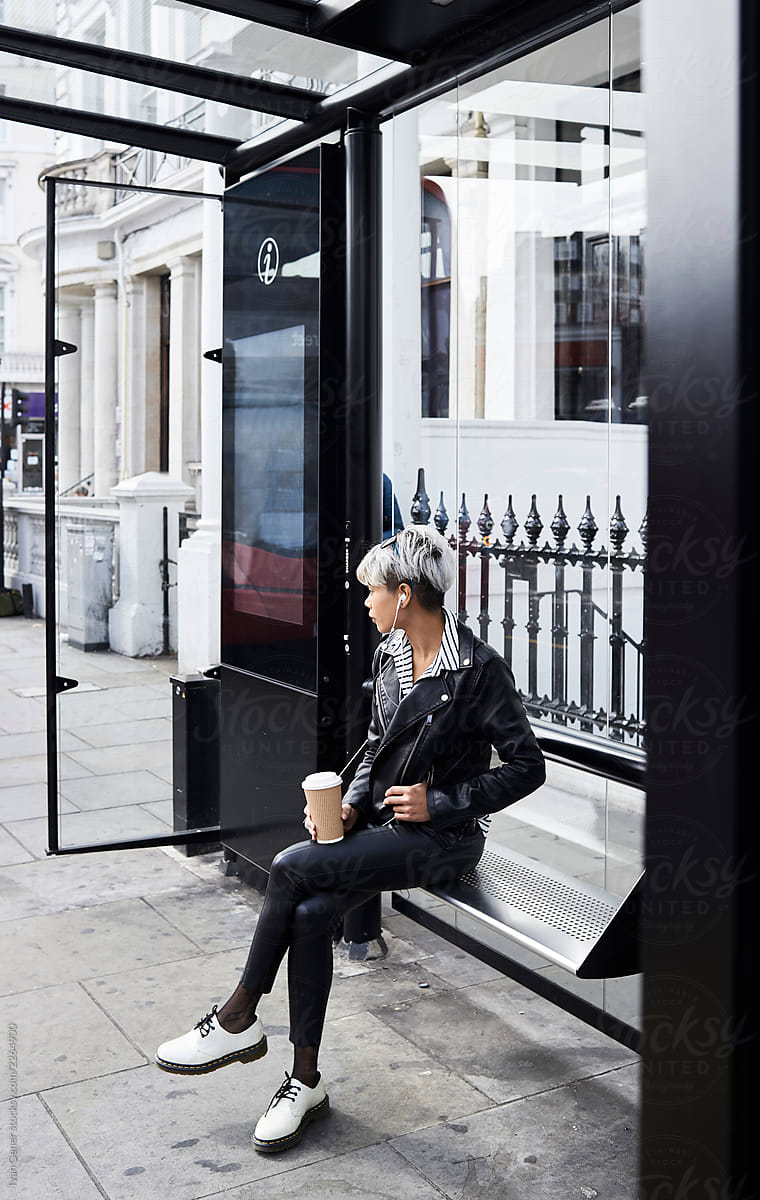 Female waiting at bus station holding coffee