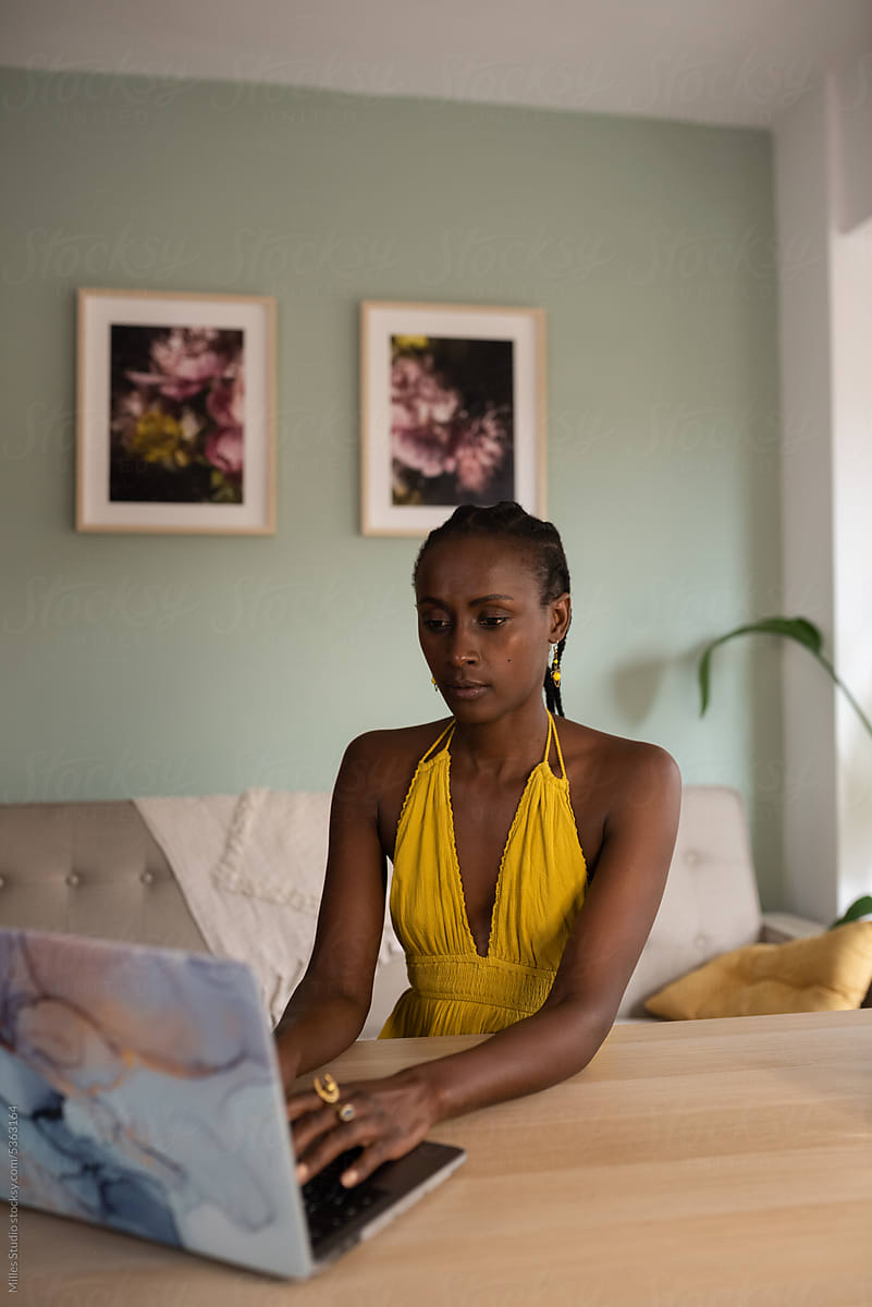 Black female freelancer working on laptop at home
