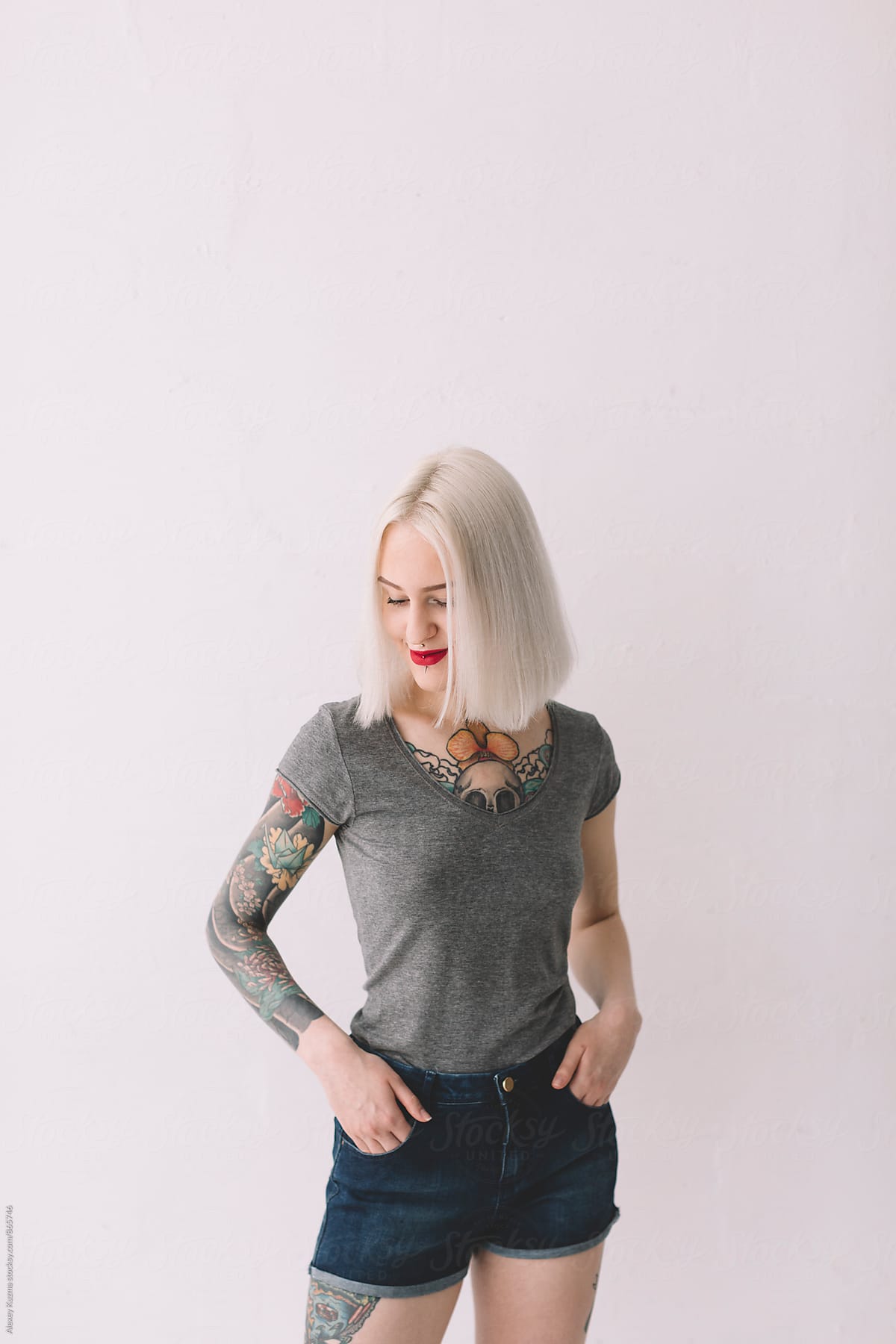 portrait of happy young blond woman with tattoos on the white background