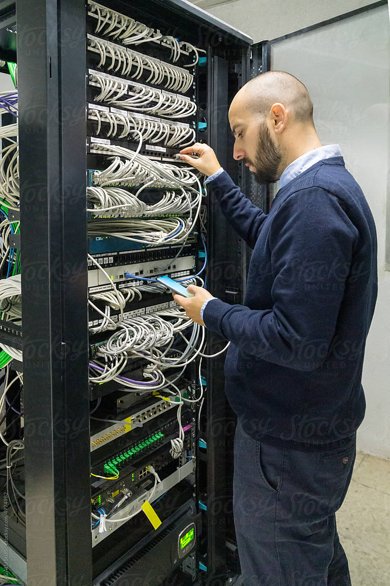Engineer working in a datacenter with a mobile phone