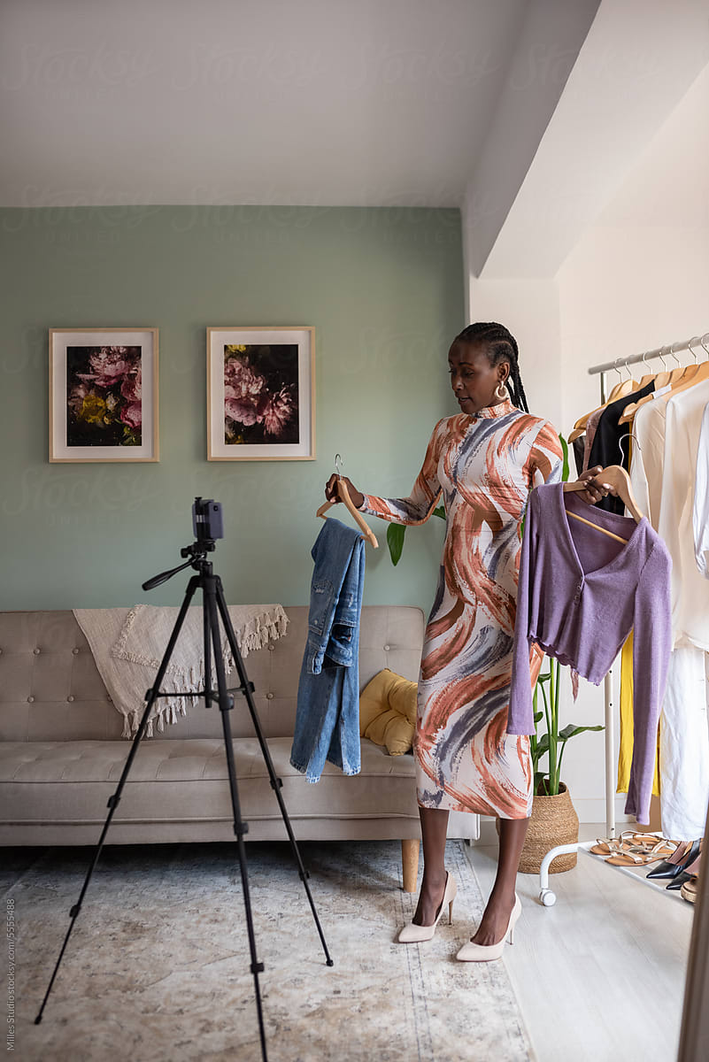Woman showing outfit to cellphone camera at home