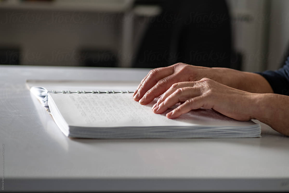 Female elderly fingers reading a book page with braille