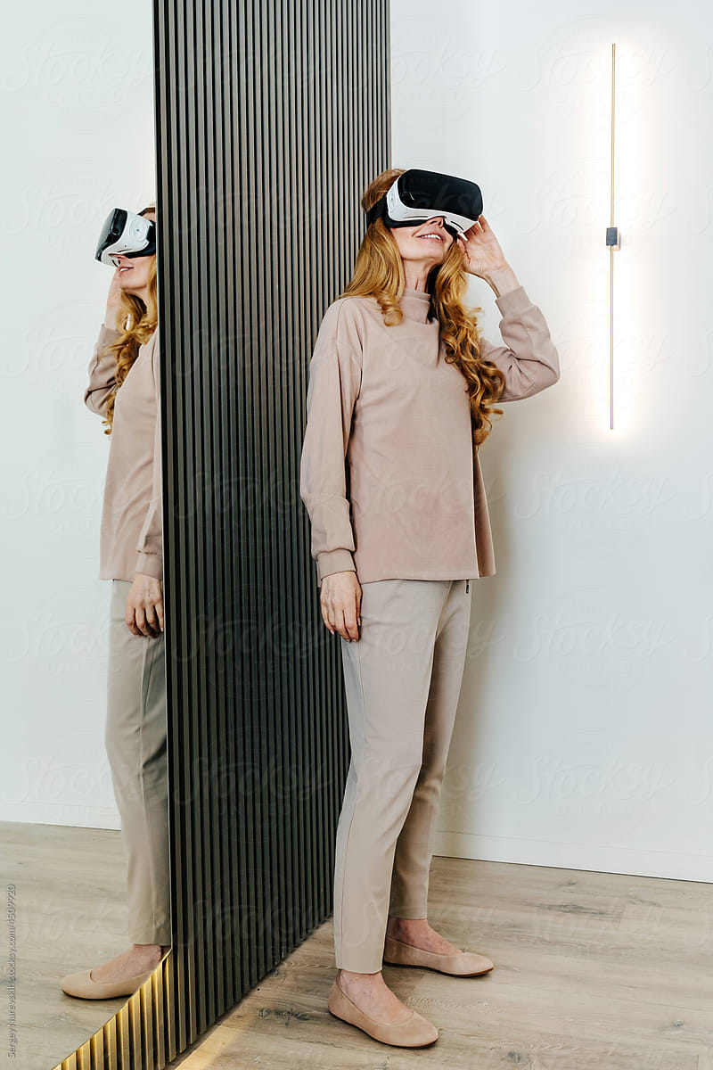 Senior woman in VR glasses near mirror