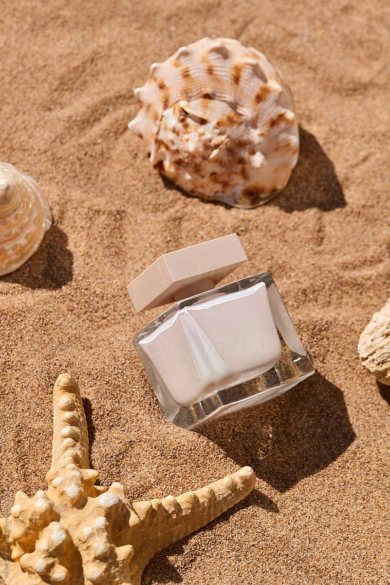 Starfish and seashells on sand with parfum fragrance bottle