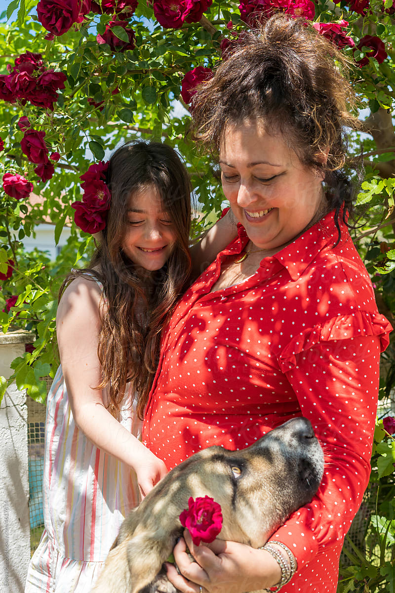 Mature woman with her granddaughter petting dog at garden