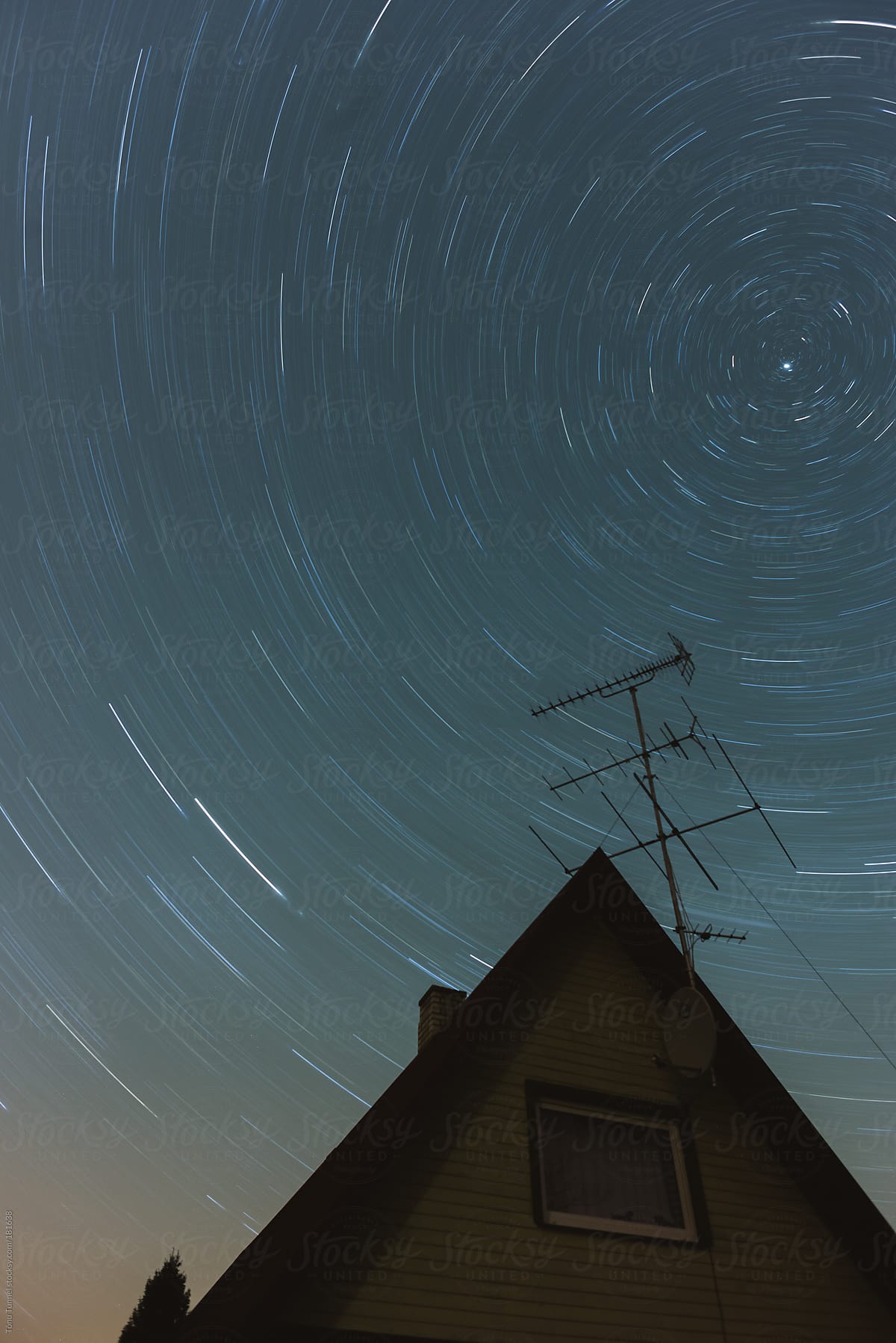 A house with an antenna under a starry sky swirling