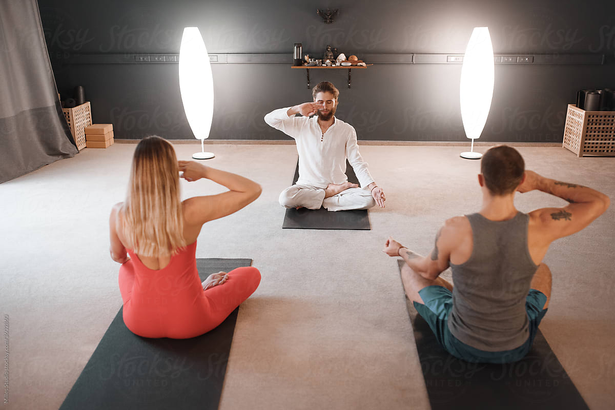 Male instructor teaching group to meditate