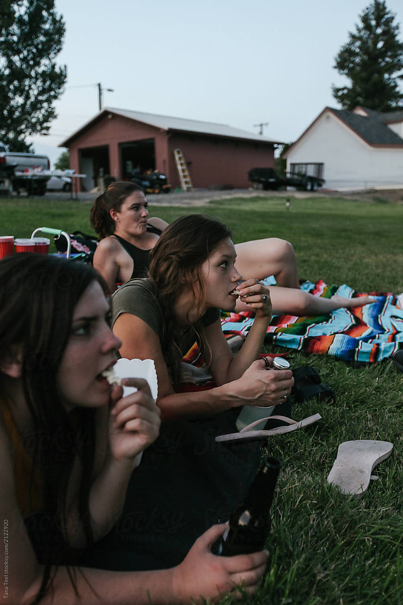 young women watch an outdoor movie in backyard