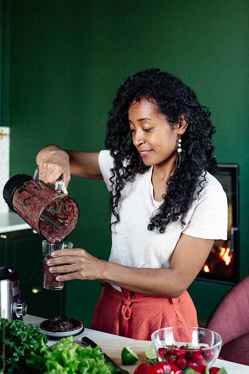Black woman preparing smoothie in glass