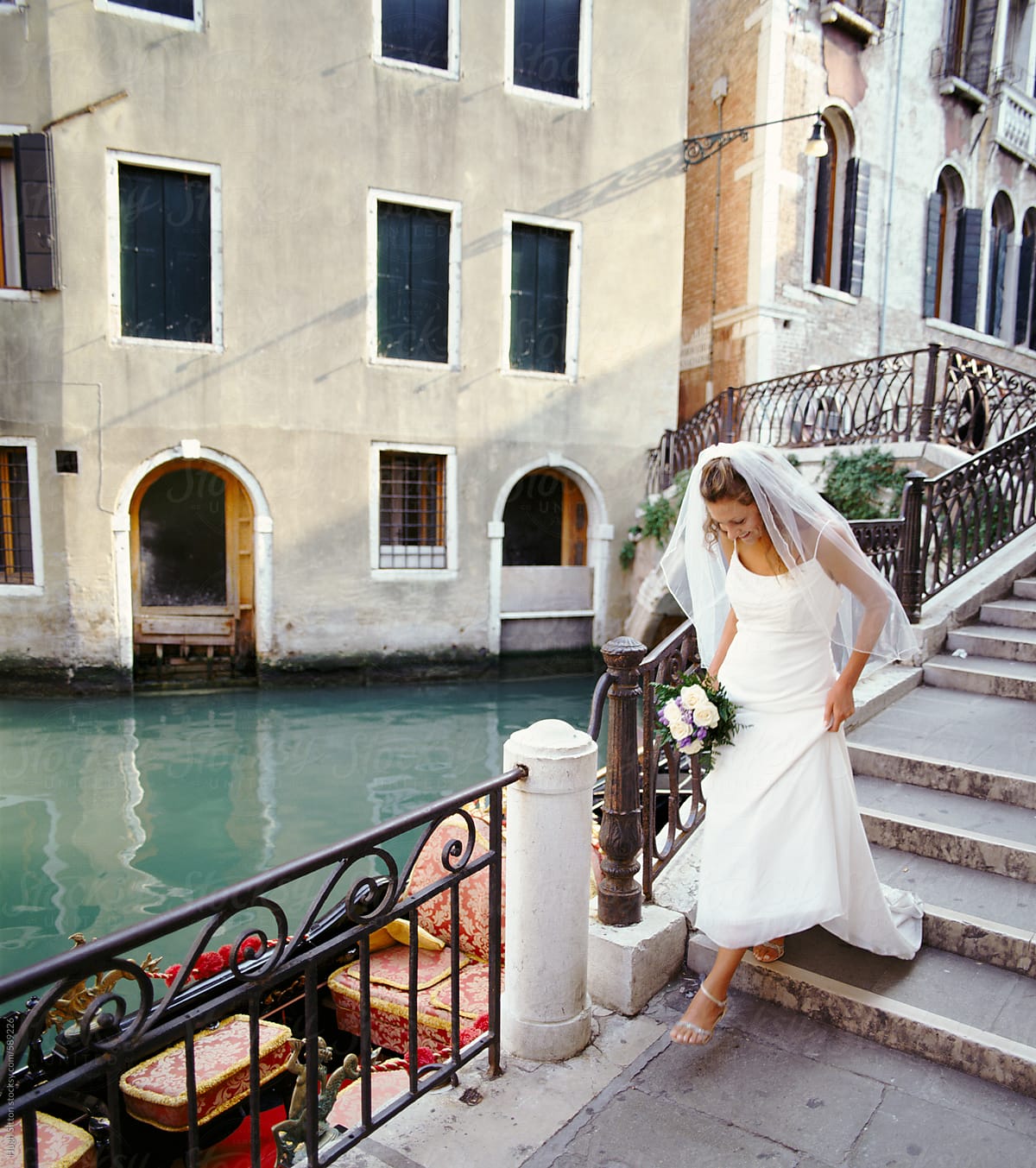 Bride hurrying down steps to her wedding. Venice. Italy.