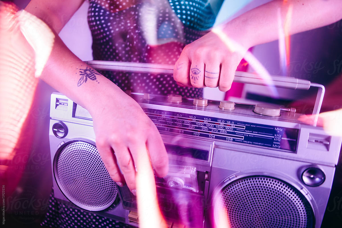 Close up of a womans hands putting a cassette tape into a ghetto blaster