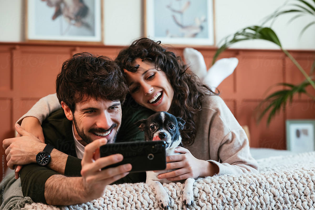 Loving couple taking selfie on smartphone on bed