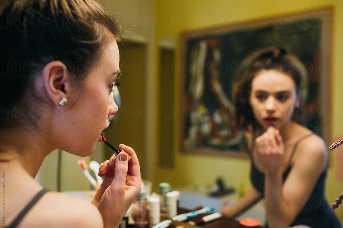 Young woman applying makeup in front of the mirror