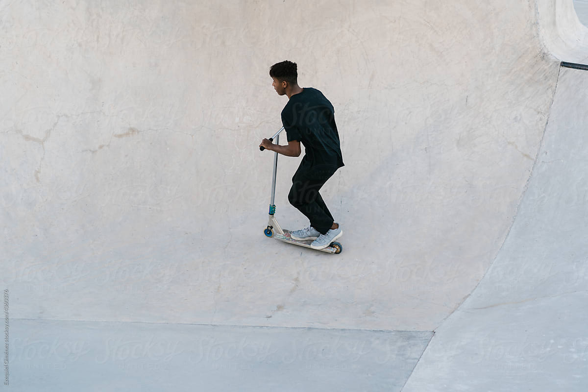 Young Colombian sportsman riding scooter in skate park