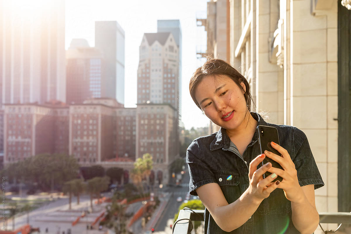 Woman Points Phone Towards City View
