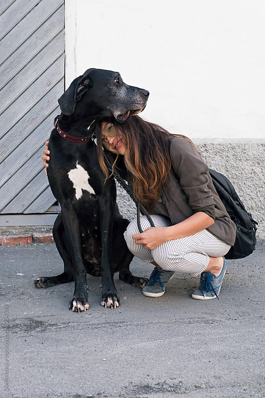 Stylishly dressed girl hugging big black dog