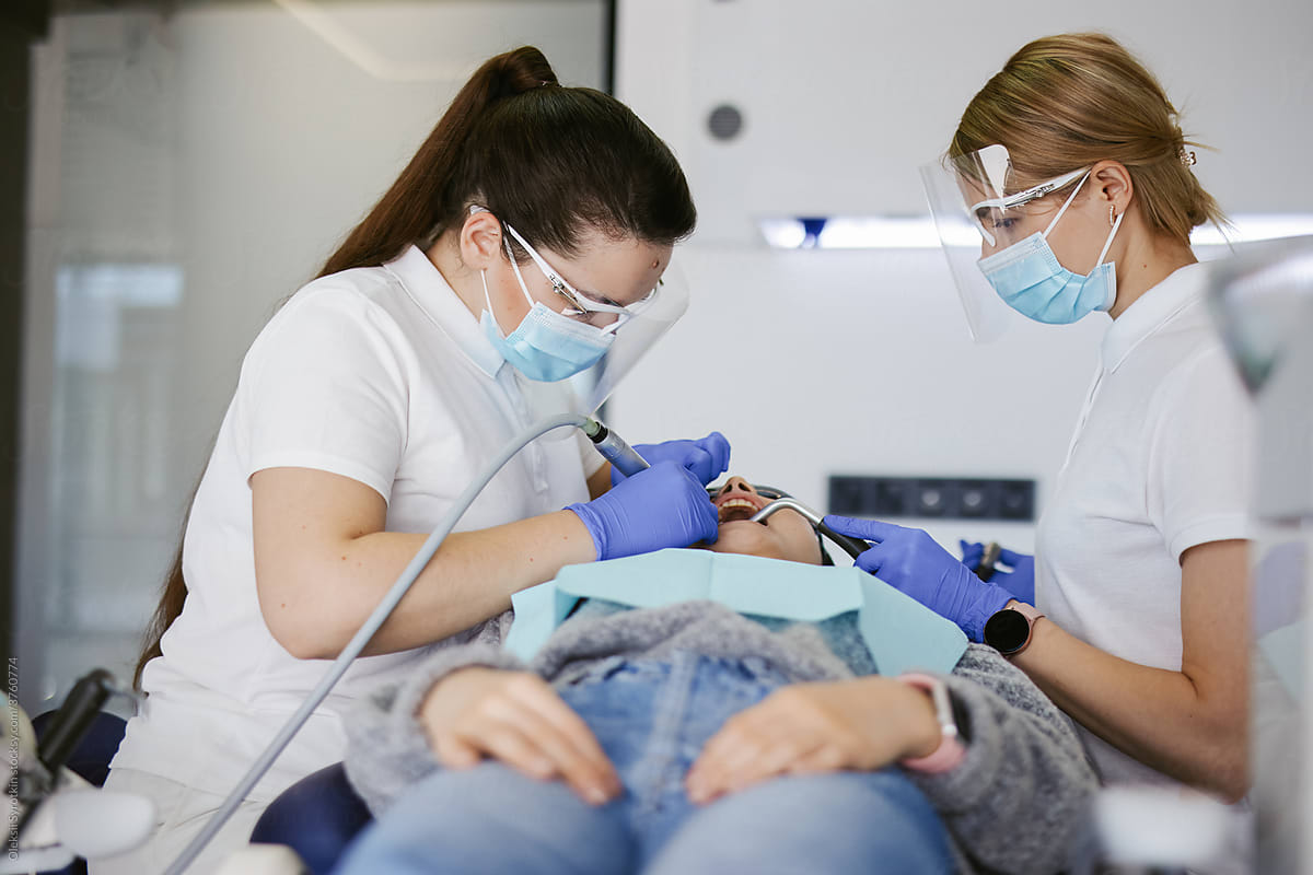Orthodontist curing her patient using handpiece dental drill in dentistry office