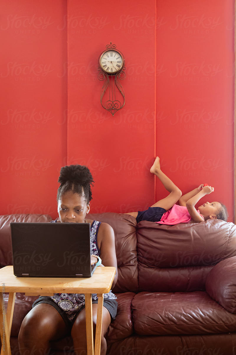 Child lounging on couch while mother works
