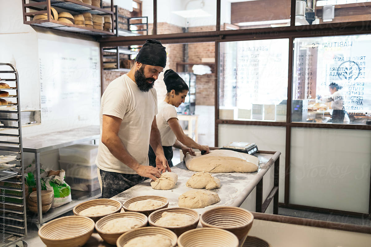 Bread Makers Kneading Dough In Bakery