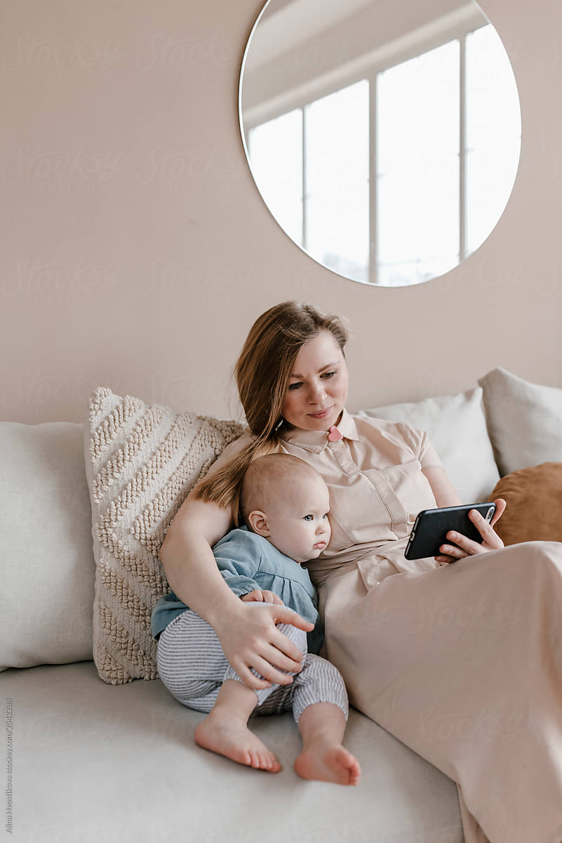 Mother with baby girl watching videos on smartphone.