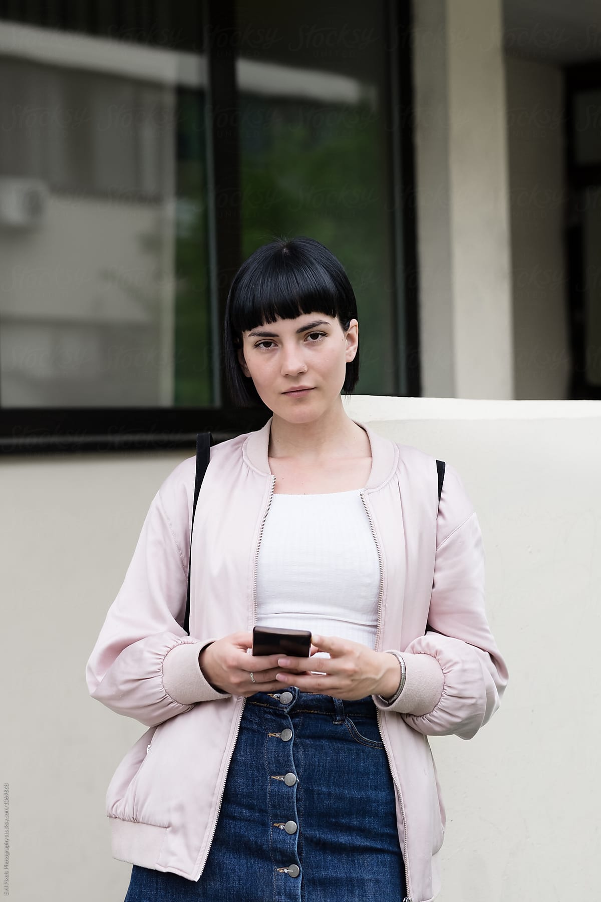 Portrait of a young female model using her phone in front of the building