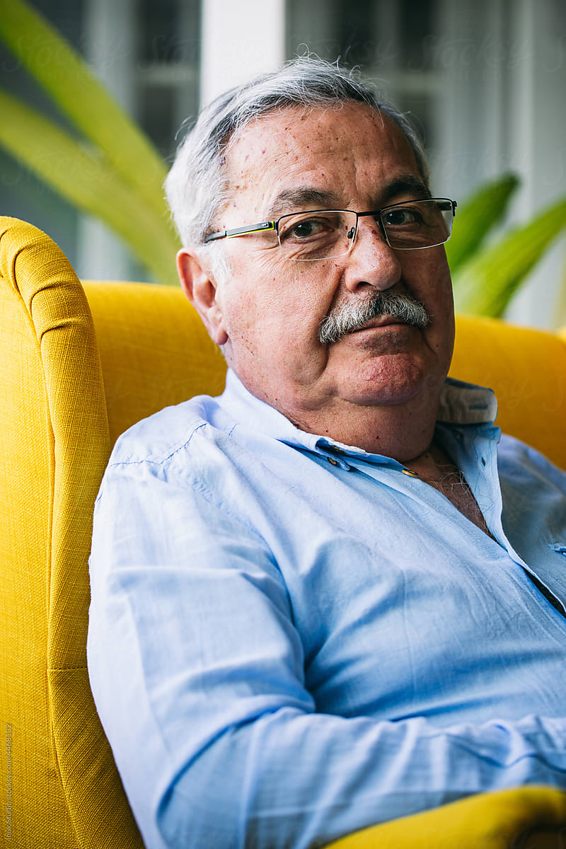 Senior man in glasses sitting in modern armchair