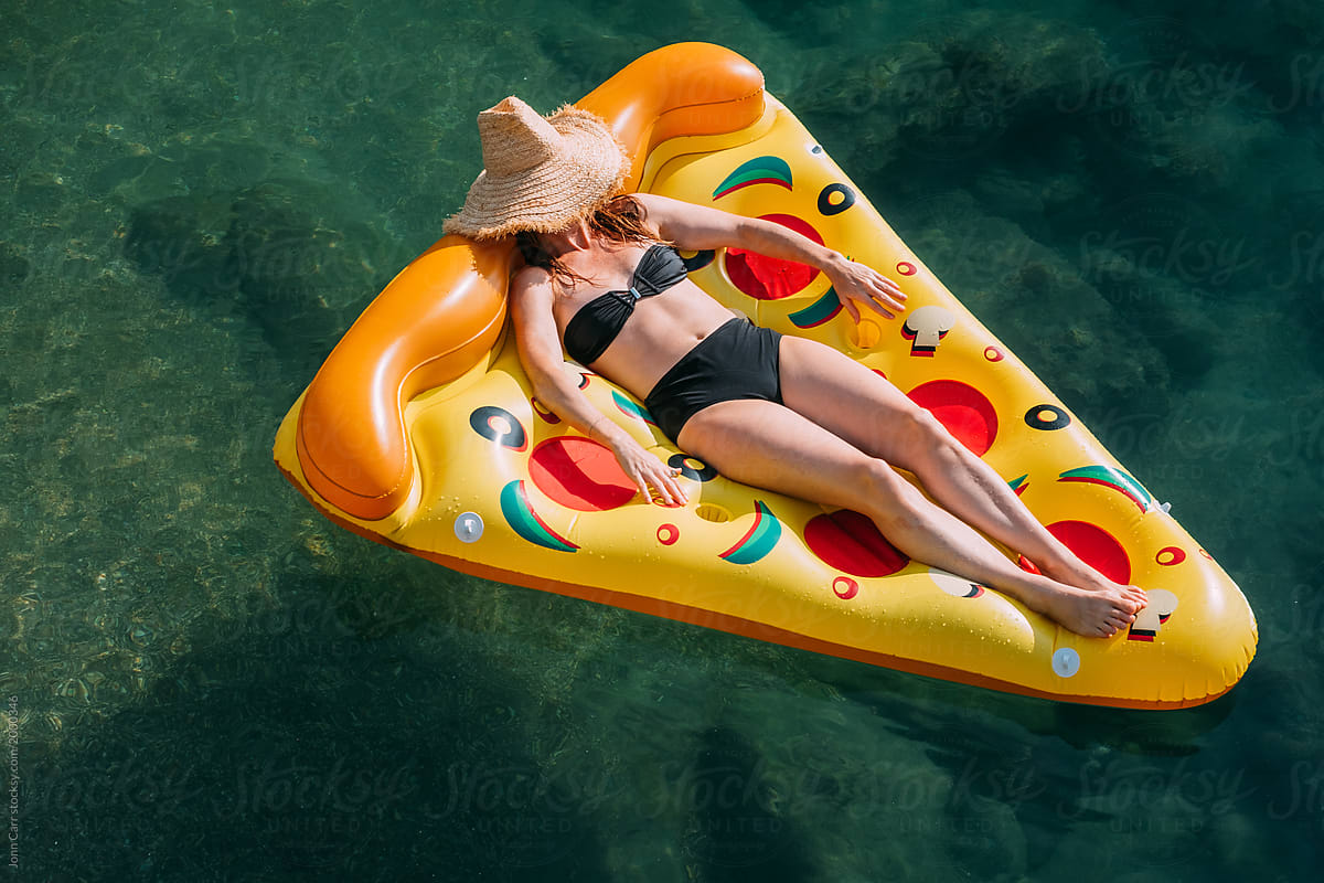 Woman floating on inflatable pizza lilo float