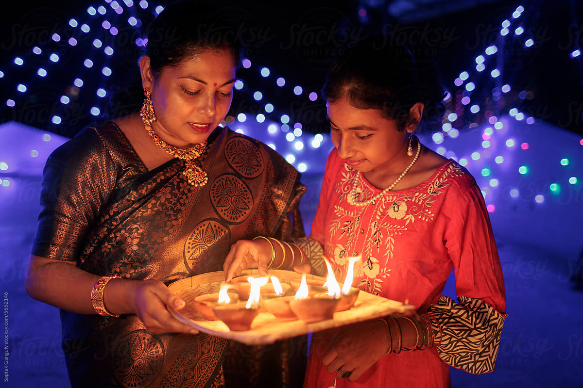 Mother and daughter celebrating diwali with earthen oil lamps