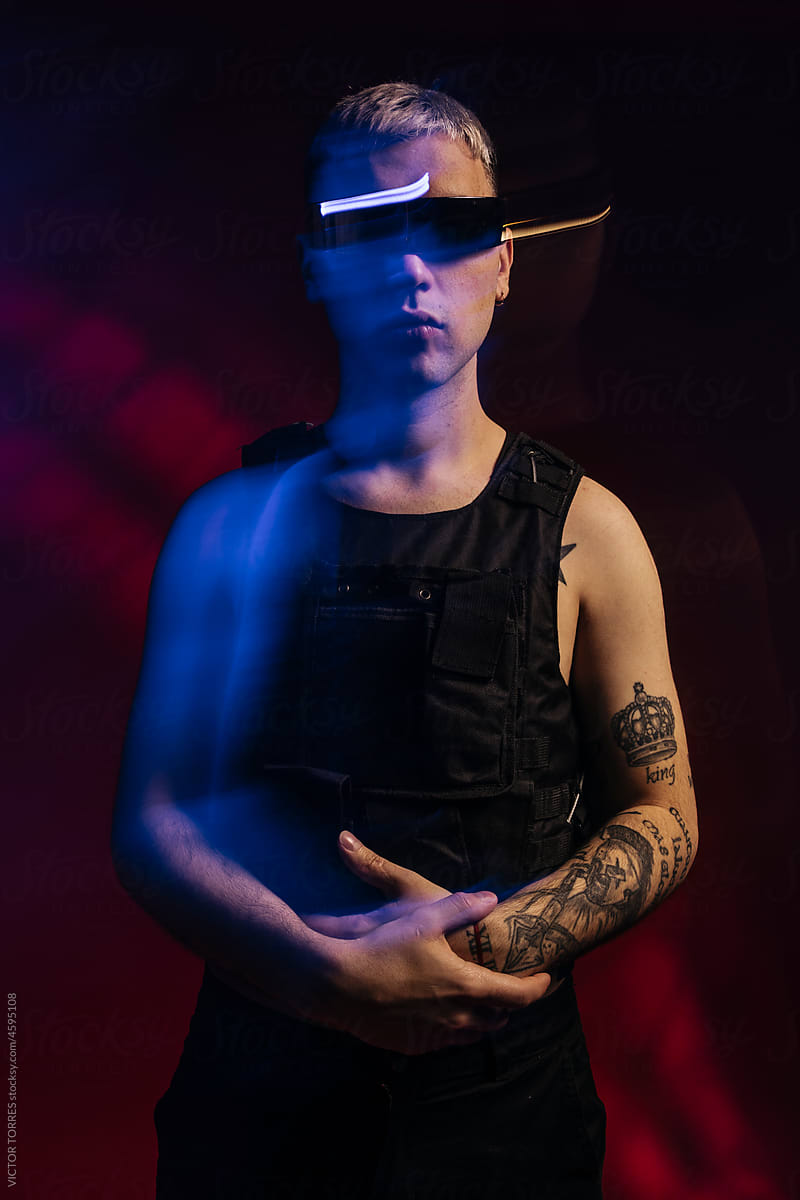 Confident tattooed man in futuristic VR goggles