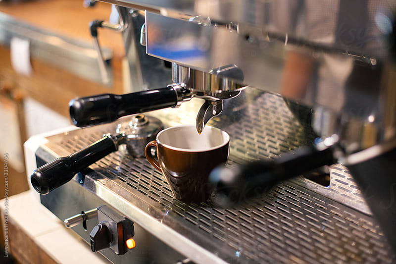 Cup of coffee being prepared using an espresso machine in a cafe.