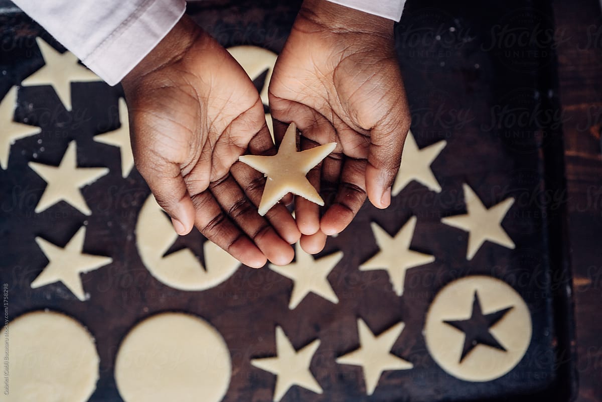 Black girl\'s hands with star shaped cookie dough