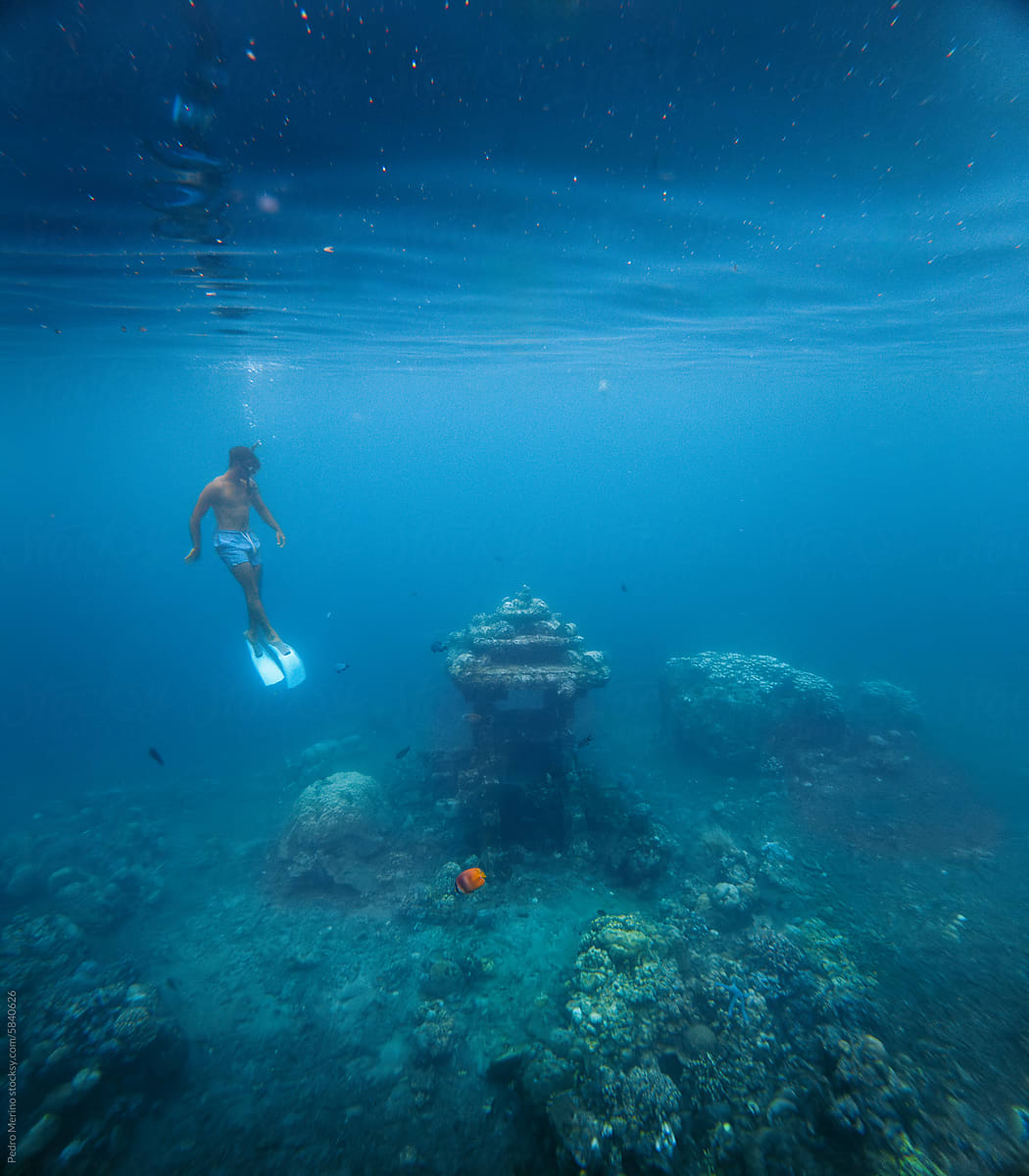 Man exploring a sunken temple in the ocean