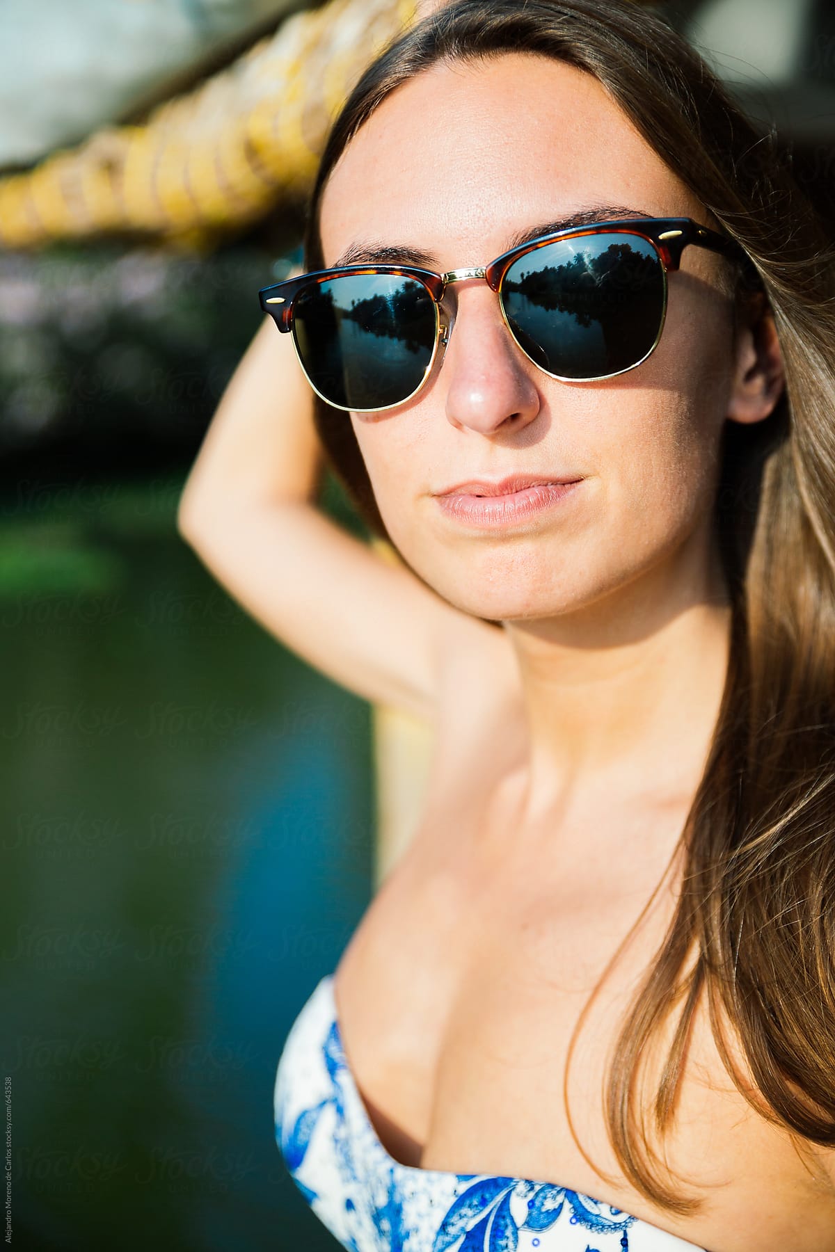Young woman close-up portrait wearing sunglasses and bikini in a boat