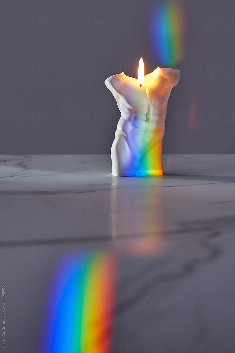 Candle with man's shape overlaid with rainbow.