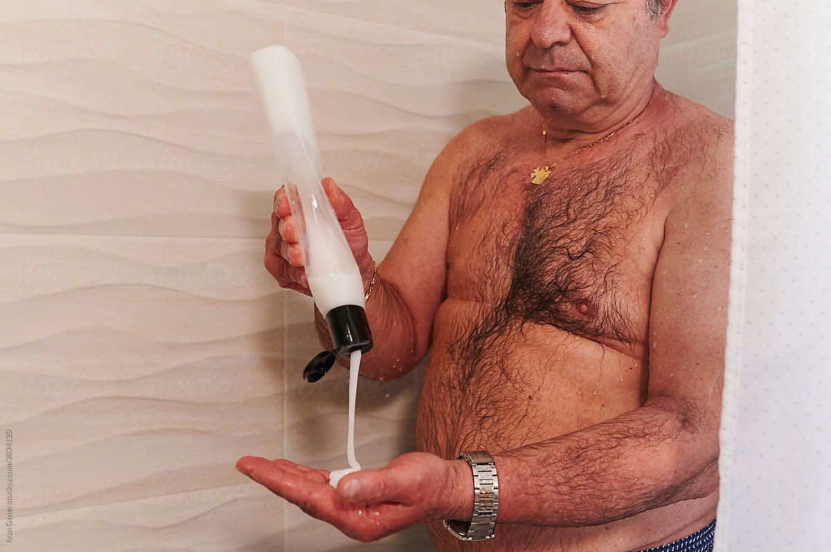 Man with a mastectomy scar shampooing in a shower