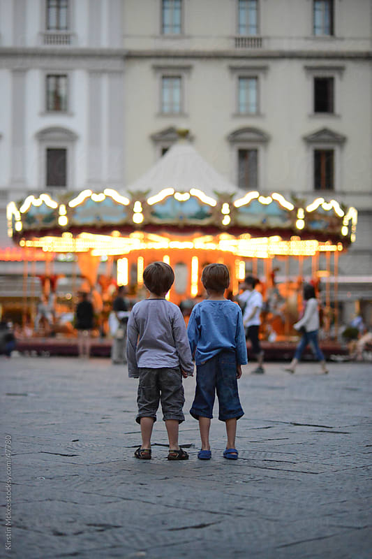 Two boys look at a merry go round.