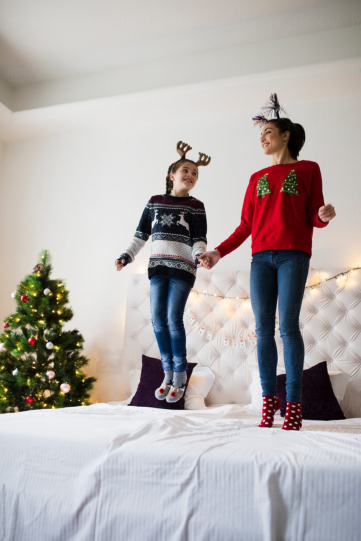 Happy sisters jumping on bed