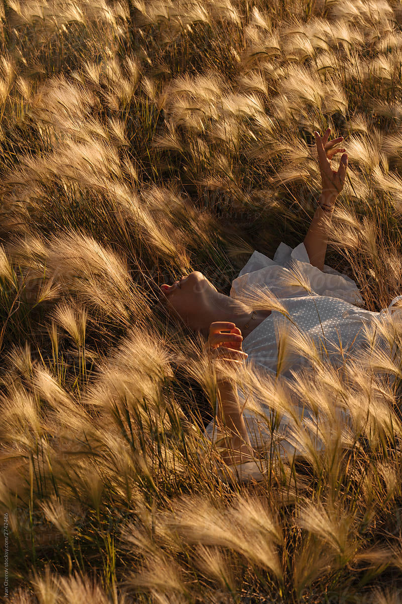 Woman Lying In Grass In Evening By Stocksy Contributor Ivan Ozerov