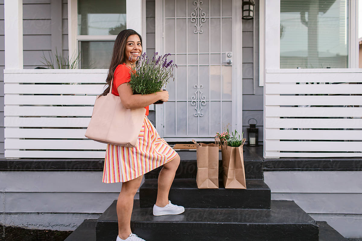 Delighted latin woman with bunch of flowers on porch