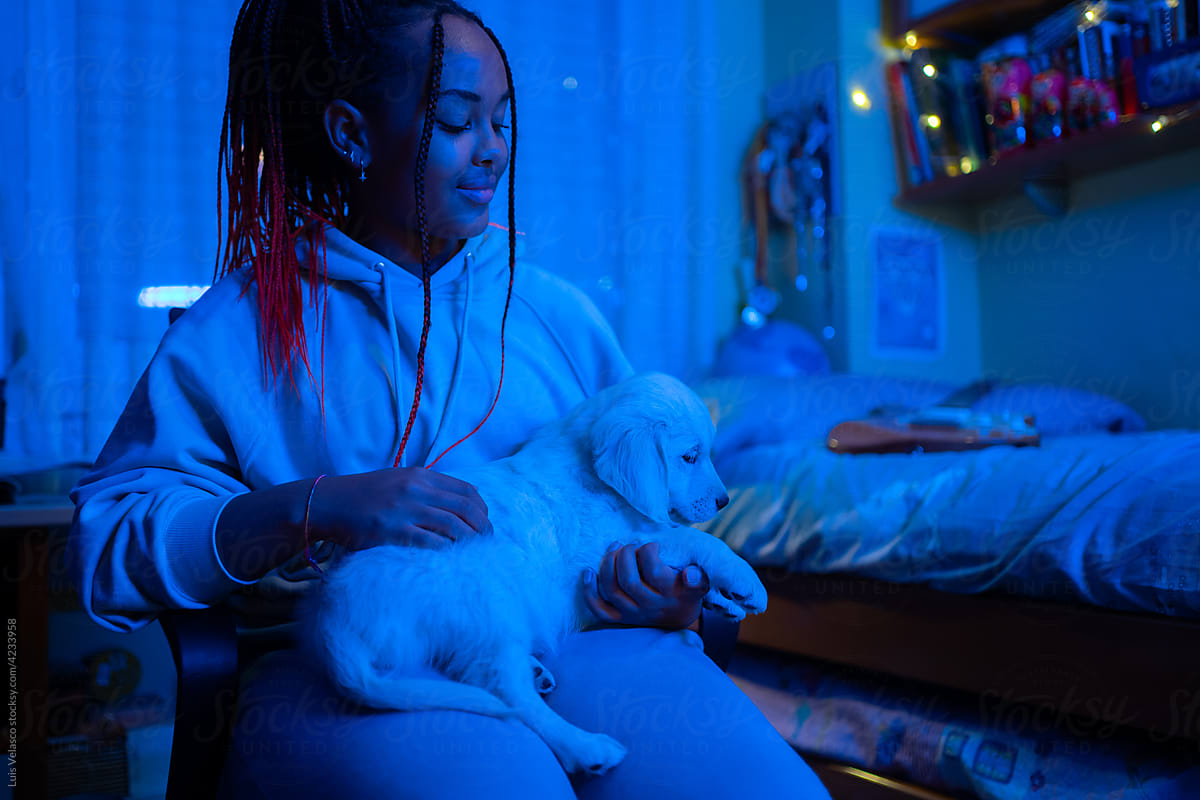 Black Kid With Her Little Dog In Her Bedroom At Night.